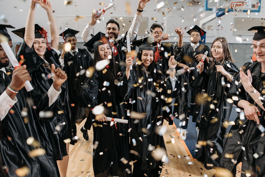 Geluid huren examenfeest | Vanaf €65 4 A diverse group of graduates celebrating with confetti indoors, capturing achievement and joy.