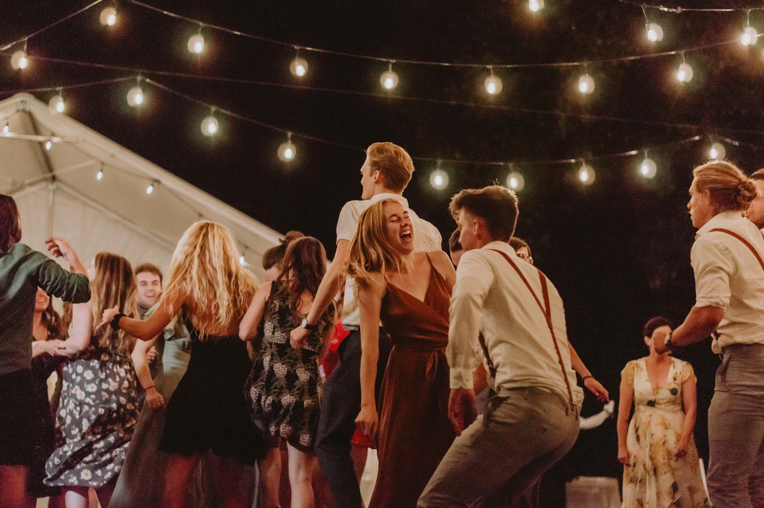 Geluid huren bedrijfsfeest | Vanaf €65 1 A lively outdoor night party with people dancing under string lights.